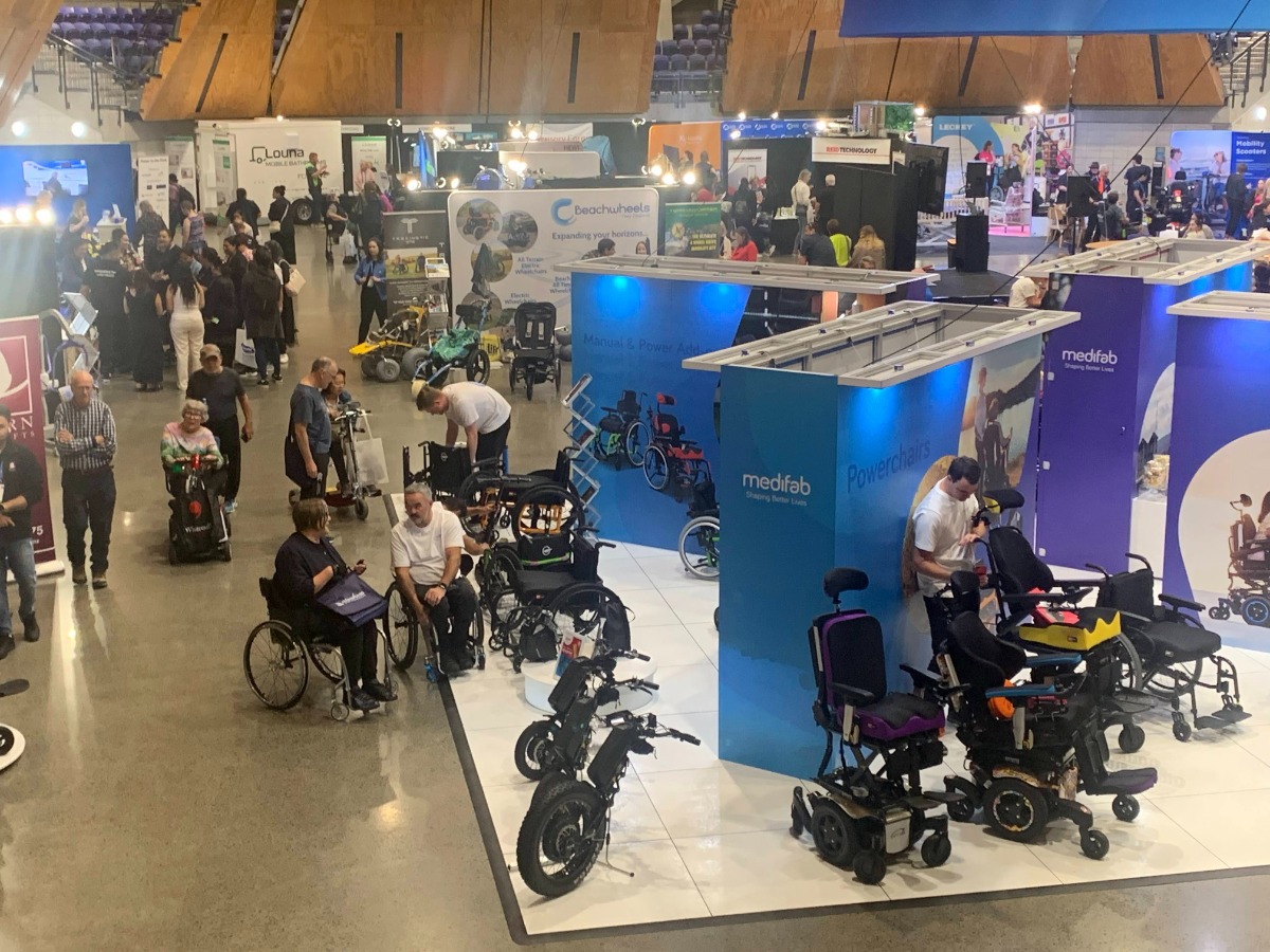 Another Expo Hall view - many powerchairs and attendees in wheelchairs in discussion
