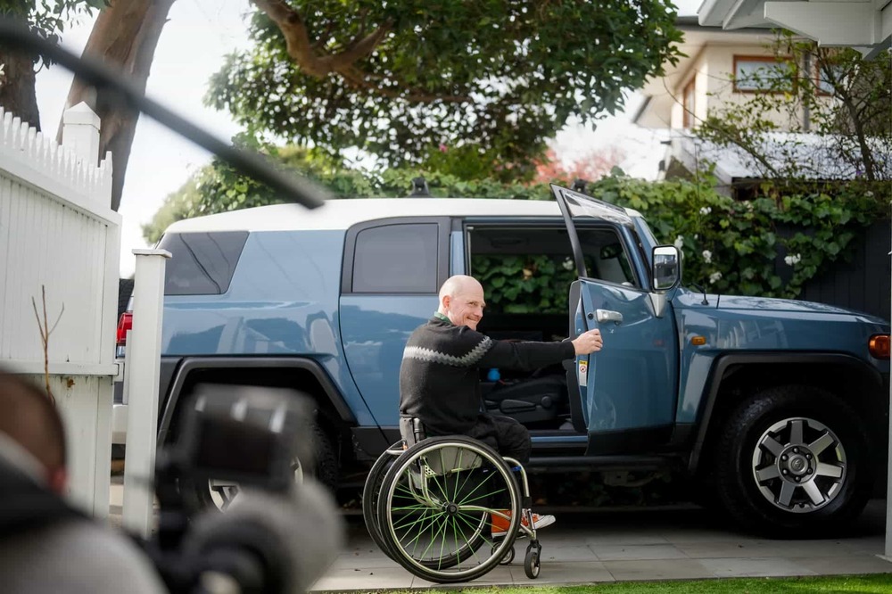 man in wheelchair closing car door
