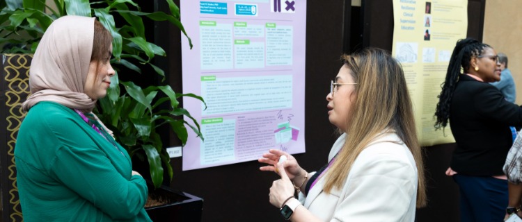 Two delegates in conversation in front of abstract posters.