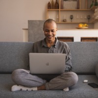 Photo of a man sitting on a couch typing on a laptop